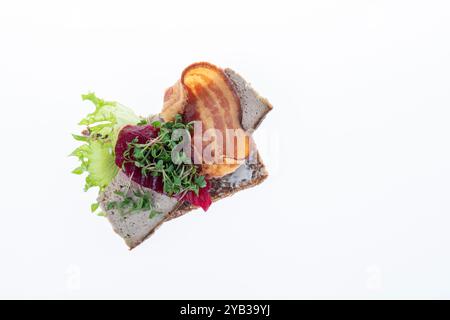 Salato smørrebrød danese con insalata di carne, pâté e bacon su rugbrød. Un classico sandwich a vista, perfetto per un pasto abbondante. Foto Stock