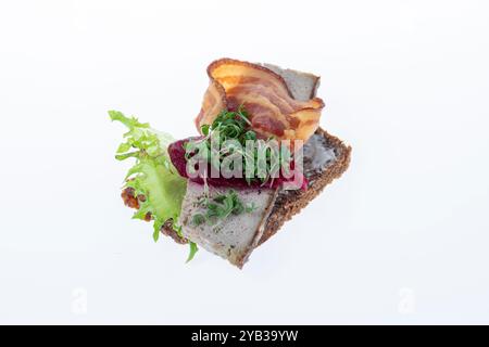 Salato smørrebrød danese con insalata di carne, pâté e bacon su rugbrød. Un classico sandwich a vista, perfetto per un pasto abbondante. Foto Stock