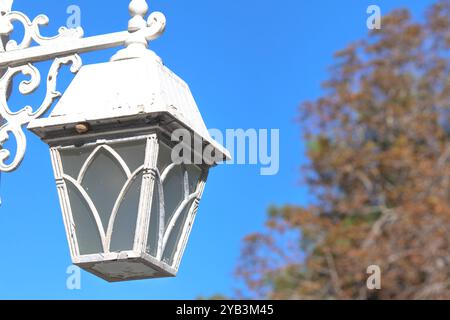 Lampione stradale vintage bianco. Lampione stradale in metallo davanti allo sfondo blu del cielo. Idea di illuminazione. Foto orizzontale. Niente persone, nessuno. Foto Stock