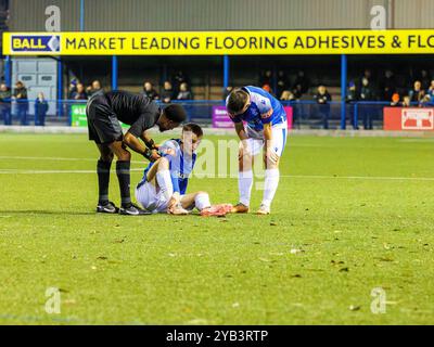 Leek Town FC, NPL Premier Division. Il giocatore di porri siede a terra tenendo il piede e viene interrogato dall'arbitro Foto Stock