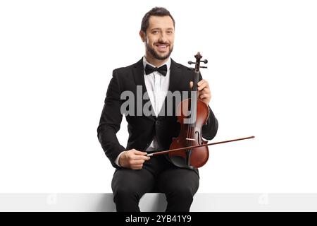 Violinista con un papillon seduto su un pannello e tenendo un violino isolato su sfondo bianco Foto Stock