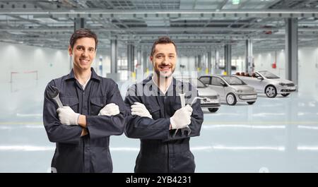 Operai delle fabbriche automobilistiche in uniformi che tengono gli attrezzi Foto Stock