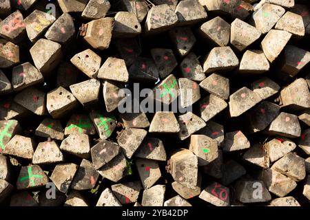 Primo piano di una pila di traverse ferroviarie in cemento scartato contrassegnate da croci verdi. Foto Stock