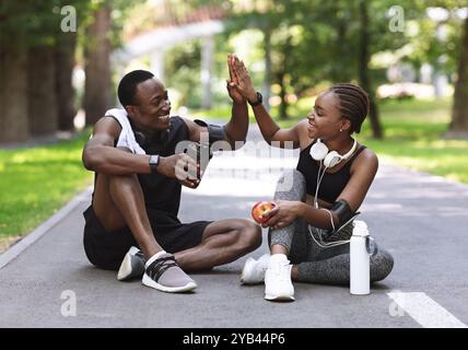 Obiettivi di relazione. Coppia Africana attiva High-Fiving l'una all'altra dopo l'allenamento all'aperto Foto Stock