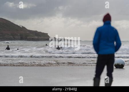 Osservatore, a fuoco tenue, osserva i surfisti che catturano le onde sulla North Sands durante la tempesta autunnale, mentre le onde si infrangono sulla spiaggia Foto Stock