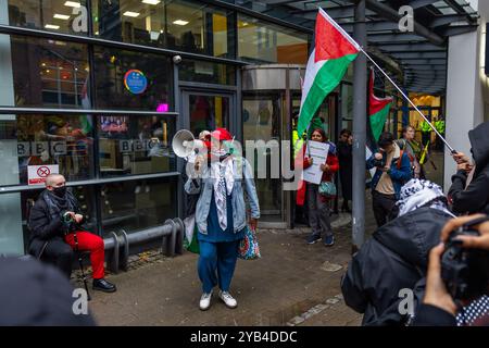 Leeds, Regno Unito. 16 OTTOBRE 2024. Mentre le persone cantano con i megafoni fuori dalle porte d'ingresso mentre i manifestanti palestinesi hanno organizzato una manifestazione fuori dagli uffici della BBC Yorkshire nel centro di Leeds accusandoli di parzialità nella copertura del conflitto di Gaza. C'era una presenza significativa della polizia e i manifestanti non sono entrati. A seguito di ciò i manifestanti si trasferirono alla stazione degli autobus di Leeds, dove un uomo era dirompente e presumibilmente assalì uno dei manifestanti, portando a parlare con entrambi gli uomini dalla polizia, non ci furono arresti. Credito Milo Chandler/Alamy Live News Foto Stock