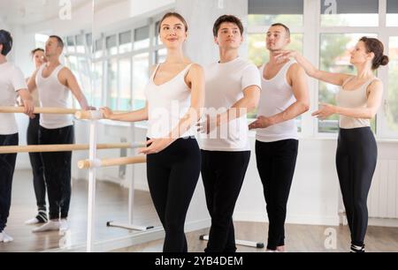 Gruppo che pratica posizioni di danza a barre con istruttore femminile Foto Stock