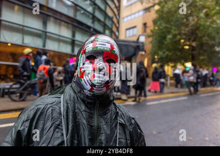 Leeds, Regno Unito. 16 OTTOBRE 2024. Maschera adesiva Man in Palestine mentre i manifestanti hanno organizzato una dimostrazione fuori dagli uffici della BBC Yorkshire nel centro di Leeds accusandoli di parzialità nella copertura del conflitto di Gaza. C'era una presenza significativa della polizia e i manifestanti non sono entrati. A seguito di ciò i manifestanti si trasferirono alla stazione degli autobus di Leeds, dove un uomo era dirompente e presumibilmente assalì uno dei manifestanti, portando a parlare con entrambi gli uomini dalla polizia, non ci furono arresti. Credito Milo Chandler/Alamy Live News Foto Stock