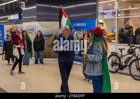 Leeds, Regno Unito. 16 OTTOBRE 2024. Un uomo afferra il megafono e in seguito presumibilmente aggredisce il protestatore pro Palestina, portando a parlare con entrambi gli uomini dalla polizia, non ci sono stati arresti. Questo avviene quando i manifestanti palestinesi hanno organizzato una dimostrazione all'interno della stazione degli autobus di Leeds in seguito alla protesta fuori dagli uffici della BBC Yorkshire nel centro di Leeds accusandoli di pregiudizi nella copertura del conflitto di Gaza. Credito Milo Chandler/Alamy Live News Foto Stock