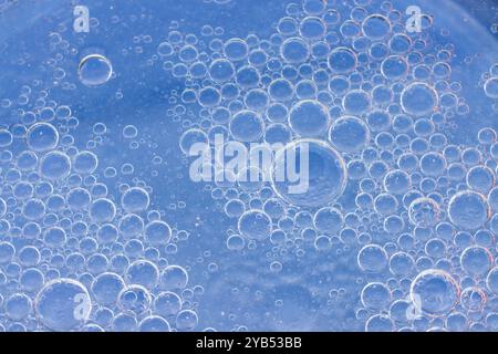 Questa foto macro presenta uno sfondo astratto riempito di numerose bolle blu di varie dimensioni. Foto Stock