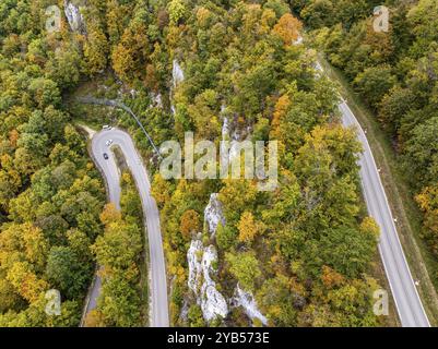 Albe sveva in autunno, Albtrauf con una foresta mista colorata e una strada di campagna tortuosa. Bad Urach, Baden-Wuerttemberg, Germania, Europa Foto Stock