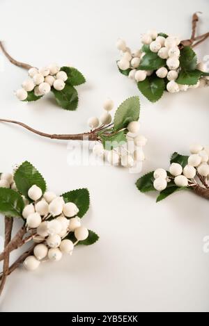 Bacche artificiali su filo per ricamo e decorazione di regali, ghirlande su sfondo bianco Foto Stock