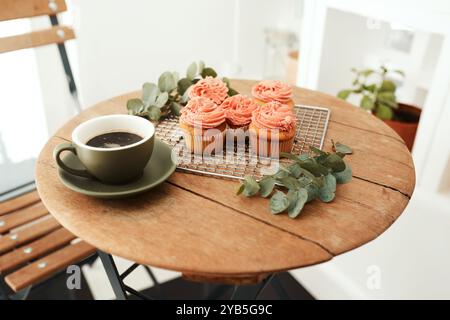 Caffè, cupcake e presentazione su un tavolo di legno per ospitalità, startup o servizio di piccole imprese. Sfondo, catering e dessert in esposizione Foto Stock