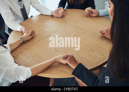 Persone, tenendosi per mano e pregando a tavola per la fede, il culto e la compassione nella religione. Lodate il gruppo, gli amici e i gesti nella struttura per la comunità Foto Stock