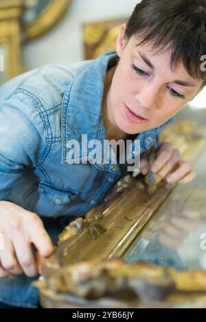 donna che lavora su un antico specchio dorato incorniciato Foto Stock