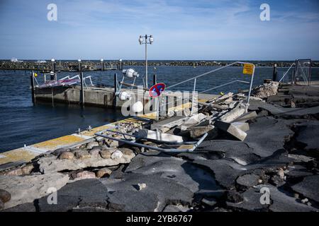 Umido, Germania. 16 ottobre 2024. Un lampione caduto e un cartello giacciono sulla banchina strappata del porto in umido. Un'ondata di tempesta baltica ha danneggiato o distrutto dighe e strutture portuali lungo la costa nell'autunno del 2023. Crediti: Hannes P. Albert/dpa/Alamy Live News Foto Stock