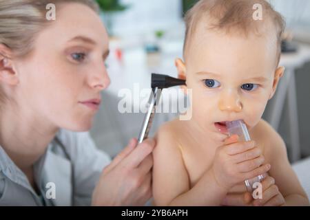 il medico esamina l'orecchio dei bambini con l'otoscopio in una stanza pediatrica Foto Stock