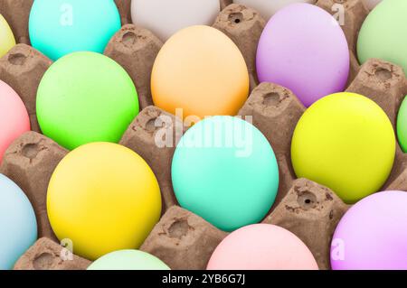 Uova di Pasqua su fondo in scatola di legno. Modello di uova di Pasqua color arcobaleno. Gruppo di uova di pasqua di fila. Foto Stock