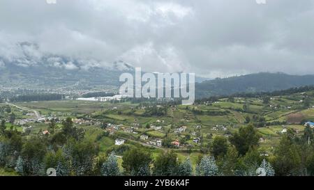 Vista panoramica tra Quito e Ibarra in Ecuador, nuvole che toccano le colline a causa dell'altitudine, lussureggianti campi verdi e piccoli villaggi sottostanti Foto Stock