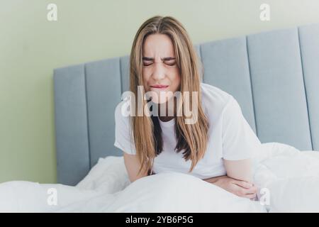 Foto di una ragazza triste stressata che soffre di mestruazioni sdraiata sul letto in casa Foto Stock