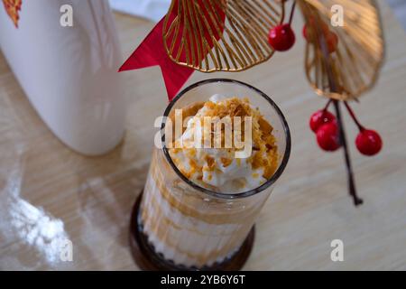 Il latte di cioccolato viene versato in un bicchiere, spruzzato mentre scorre e versato sul tavolo. Frullato di cioccolato Foto Stock