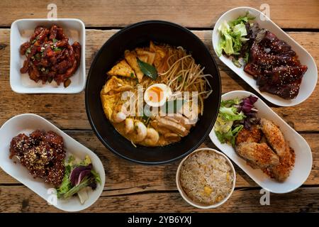 Piatti asiatici selezionati, tra cui Laksa al curry, pollo dolce e acido, ali di pollo al barbecue coreane speziate e kimchi Foto Stock