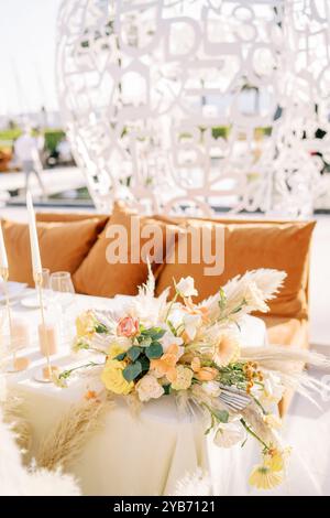 Un bouquet di fiori si erge su un tavolo vicino a un divano con cuscini Foto Stock