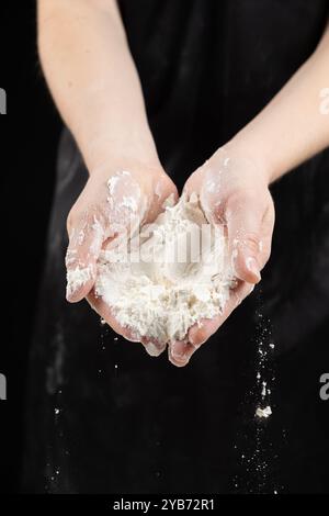 La consistenza della farina di grano bianco, la farina fuoriesce dalle mani del cuoco Foto Stock