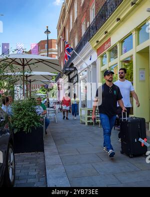 Londra - 06 15 2022: Persone che camminano con le valigie su Elizabeth St e clienti seduti al ristorante Foto Stock