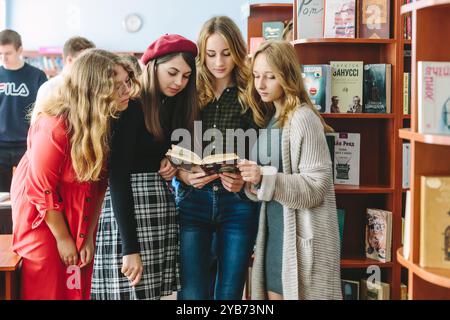 Romny, Ucraina, 29 settembre 2019: Giovani donne, studenti stanno in piedi in un ambiente accogliente della biblioteca e leggono un libro Foto Stock