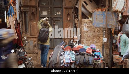 Nuova Delhi, Delhi, India - 4 febbraio 2024: Un uomo vende vestiti dal suo carrello sulla strada principale del Bazar, Paharganj. Foto Stock