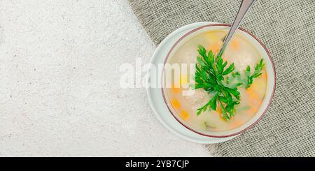 Abbondante zuppa di nozze italiana fatta in casa con verdure e polpette. Brodo vegetale con pollo e fagioli, cibo confortevole. Sfondo in gesso chiaro, striscione Foto Stock