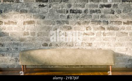 Panca in velluto beige vecchio stile su pavimento in legno lucido davanti a una parete in mattoni invecchiati, un elegante arredo in stile rustico Foto Stock