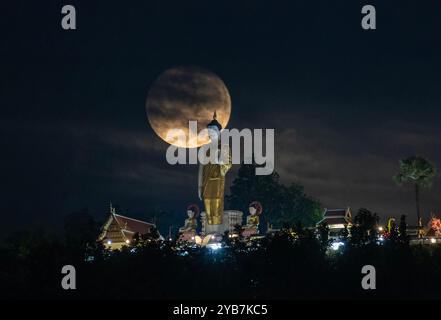 Chiang mai, Thailandia. 17 ottobre 2024. La luna piena, vista su una delle sue orbite più vicine alla Terra, galleggia vicino alla statua di Buddha in piedi a Wat Phra That Doi Kham. La luna piena orbita più vicina alla Terra, nota come "Superluna", facendo apparire la luna più grande e luminosa del solito. Credito: SOPA Images Limited/Alamy Live News Foto Stock