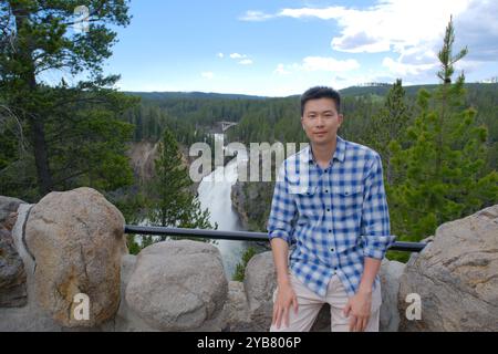 Turista asiatico maschile e cascate superiori del fiume Yellowstone nel parco nazionale di Yellowstone Foto Stock
