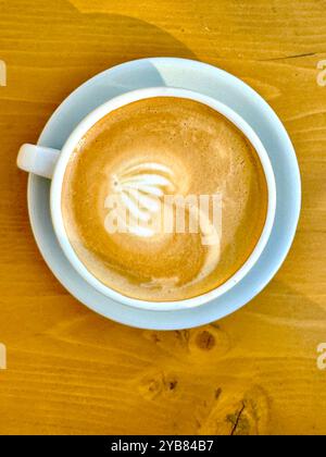 Tazza bianca con caffè al cortado - su un tavolo di legno. Nessuna persona Foto Stock