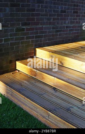 Gradini di legno di un ponte contro un muro di mattoni all'alba Foto Stock
