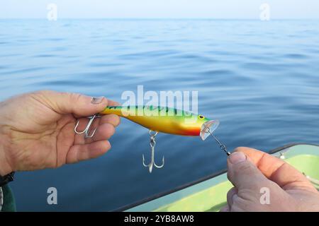primo piano di un pescatore con un richiamo per la pesca del branzino in una barca Foto Stock