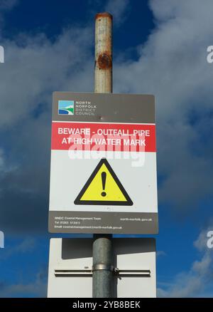 Un segnale per essere a conoscenza della Spring Beck Outfall Pipe presso High Water Mark sulla costa nord del Norfolk a Weybourne, Norfolk, Inghilterra, Regno Unito. Foto Stock