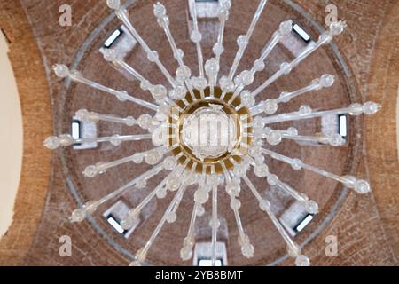 Vista simmetrica dal basso dell'enorme cupola in mattoni della fabbrica reale di vetro di la Granja de San Ildefonso. In primo piano un enorme lampadario Foto Stock