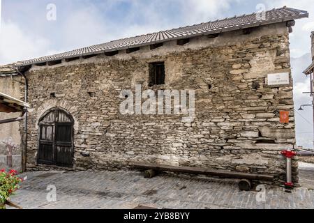 Paesaggio urbano con un'antica casa in pietra e un'immondizia nello storico villaggio montano della valle di Valchisone, girato alla luce di una caduta a Usseaux, Torino, Italia Foto Stock