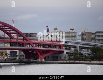 Paesaggio urbano con vista panoramica del luminoso ponte rosso Ohashi che collega la terraferma all'isola di Port presso il porto di Kobe nel Kansai, Hyōgo Giappone. Foto Stock