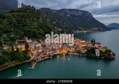 Magico crepuscolo sul Villaggio di Varenna sul Lago di Como: Una serena veduta aerea del tranquillo Waterfront Gem d'Italia, incastonato tra le Montagne e il Reflective Foto Stock