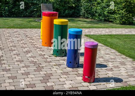 Vibranti strutture cilindriche sorgono su un'area pavimentata in un parco, circondata da erba e alberi, creando un ambiente divertente per i bambini Foto Stock