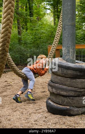 Ragazzo che si diverte all'aperto. Bambini appesi alla fune, dondolano nel parco. Foto Stock