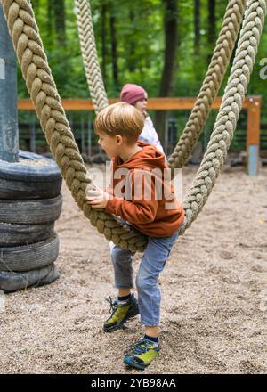 Ragazzo che si diverte all'aperto. Bambini appesi alla fune, dondolano nel parco. Foto Stock