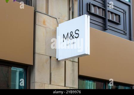 Primo piano di un cartello di un moderno punto vendita con le lettere "M&S" e il testo "EST. 1884 ». Il cartello è montato su un muro di pietra, che mostra una truffa Foto Stock