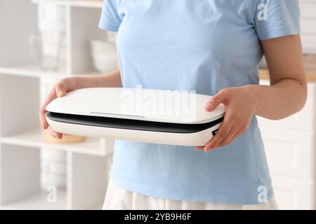 Giovane donna con macchina sigillatrice sottovuoto per alimenti in cucina Foto Stock