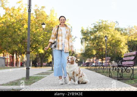 Giovane donna con il cane pastore australiano che cammina nel parco Foto Stock