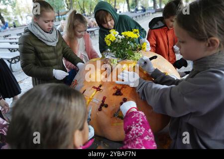 Riga, Lettonia. 17 ottobre 2024. I bambini incidono su una zucca durante il più grande campionato lettone di zucca a riga, Lettonia, 17 ottobre 2024. Il 19° campionato di zucca più grande della Lettonia si è tenuto qui giovedì. Crediti: Edijs Palens/Xinhua/Alamy Live News Foto Stock